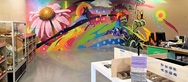 Colorful mural on wall of sustainability gallery features flowers and animals