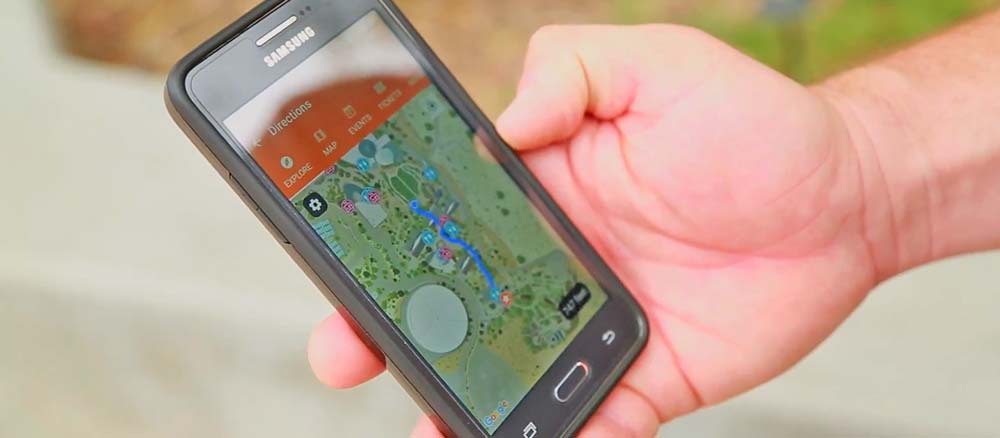 A person holding a smartphone displaying an interactive map on the Springs Preserve mobile app.